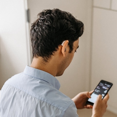 Man with hearing aid looking at phone