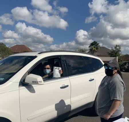 Woman in car picking up curbside hearing aids.